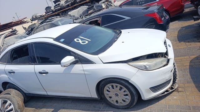 White Ford Focus sedan car for parts with front-end damage, crumpled hood and headlight, Sharjah market