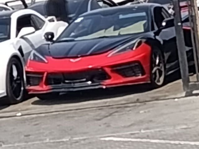 Black Chevrolet Corvette coupe with red front bumper, hood and headlights, car for parts on Sharjah market