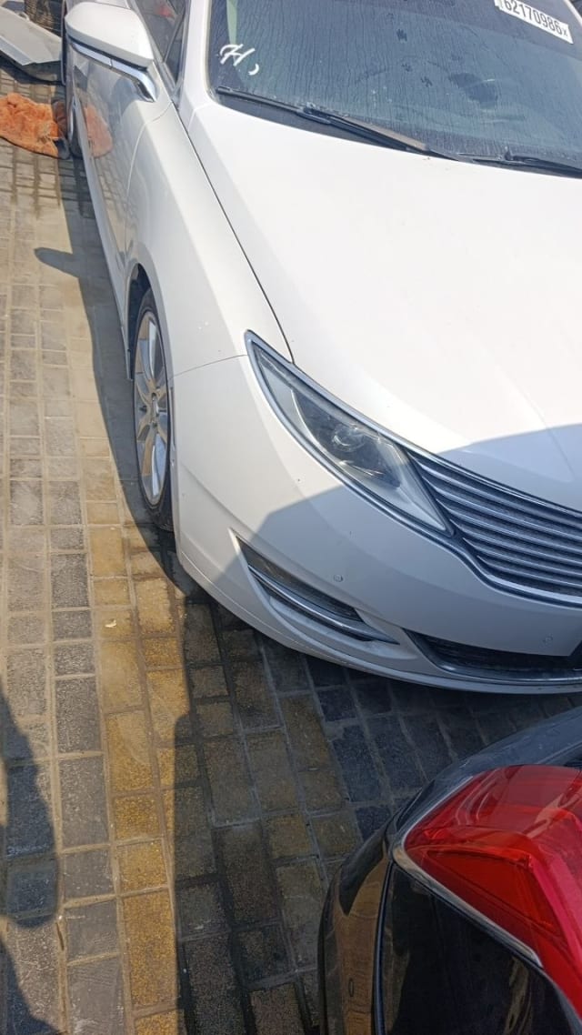 White Lincoln MKZ sedan front left corner showing headlight, grille, bumper and hood, Sharjah market