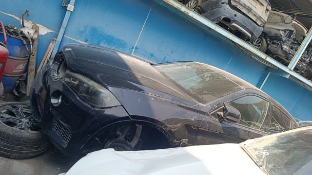 Black BMW X6 car for parts — front bumper, headlights, hood and fender, wheel removed, Sharjah market