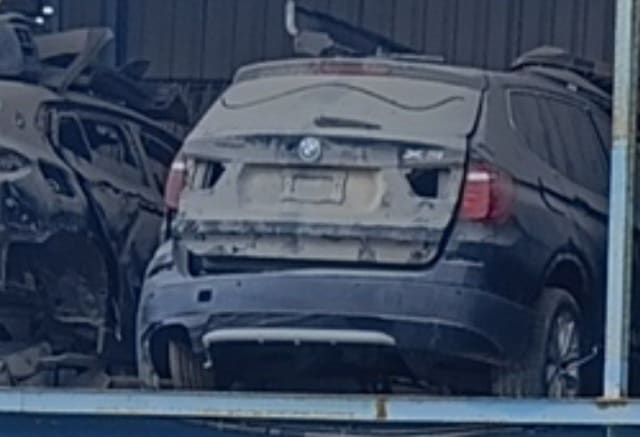 Dusty dark BMW X3 SUV for parts, rear view with tailgate, tail lights and rear bumper, Sharjah market