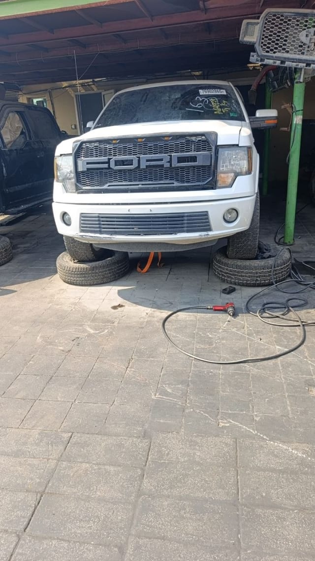 White Ford F-150 pickup for parts, front view with FORD honeycomb grille, headlights and bumper, Sharjah market