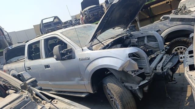 Silver Ford F150 crew cab car for parts, hood open, front end stripped, doors and fender intact, Sharjah