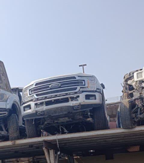 White Ford F150 pickup halfcut front view: grille, headlights and bumper on a rack, Sharjah market