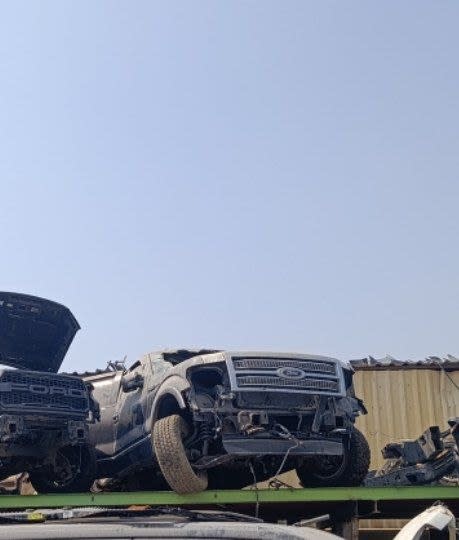 Dark grey Ford F150 pickup halfcut with chrome grille, cab and front wheels on a rack, Sharjah market