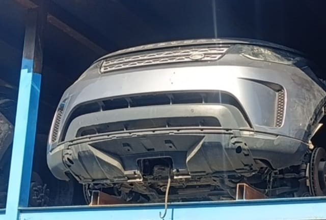 Grey Land Rover Discovery Sport front halfcut — bumper, grille and headlight on rack, Sharjah market