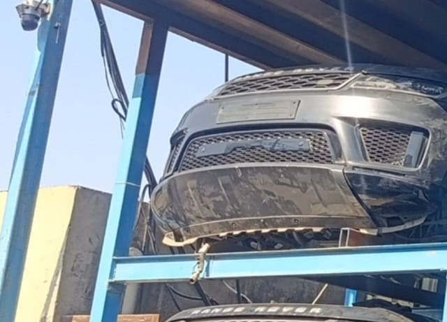 Dark Range Rover Sport halfcut front bumper, mesh grille and headlight on a blue rack, Sharjah market