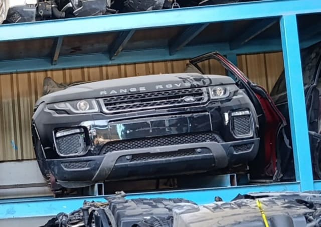 Black Range Rover Evoque front halfcut with bumper, grille, headlights and hood on a rack, Sharjah market