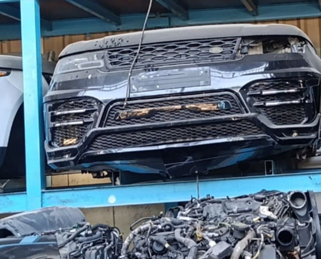 Dark blue Range Rover Sport front halfcut with bumper, grille and intakes on a rack, Sharjah market