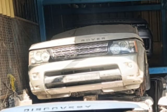 White Range Rover Sport front halfcut with bumper, grille, headlights and hood on a rack, Sharjah market