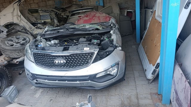 Silver Kia Sportage SUV front halfcut: grille, bumper, headlight and open engine bay, Sharjah market