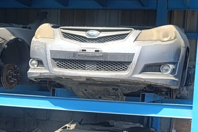 Silver Subaru Legacy front halfcut on blue rack: bumper, grille, headlights and fog lights, Sharjah market