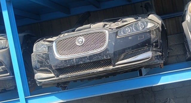 Black Jaguar XF front halfcut, mesh grille, headlights and bumper on a blue rack, Sharjah market