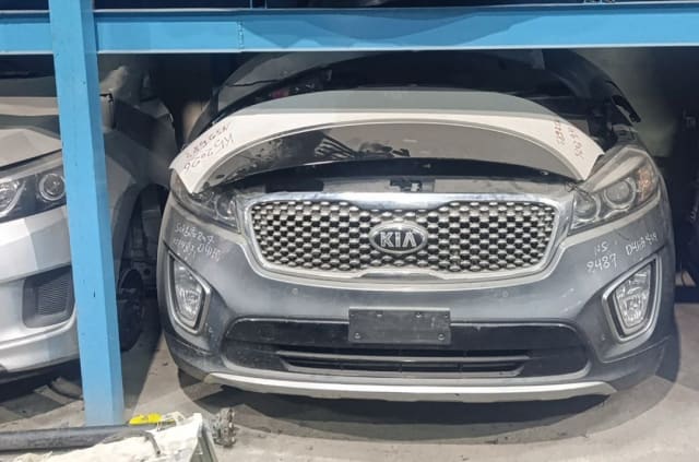 Grey Kia Sorento front halfcut with bumper, grille, headlights and hood on a rack, Sharjah market