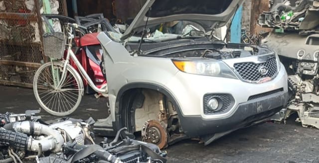 Silver Kia Sorento front halfcut with hood open, showing bumper, grille, headlights and brake disc, Sharjah market
