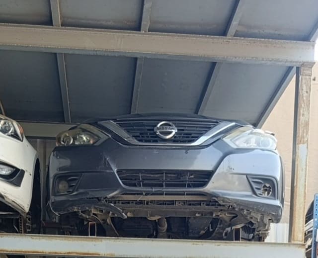 Dark grey Nissan Altima front halfcut on rack — bumper, grille and headlights, Sharjah market