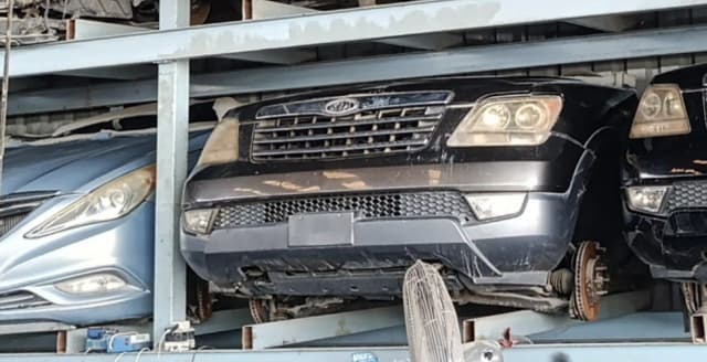 Dark grey Kia Mohave front halfcut on rack — bumper, grille, headlights and brake discs, Sharjah market