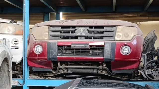 Dark red Mitsubishi Pajero front halfcut, bumper, grille, headlights and fog lights on rack, Sharjah market