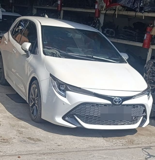 White Toyota Corolla hatchback car for parts, front view with bumper, grille and headlights, Sharjah market
