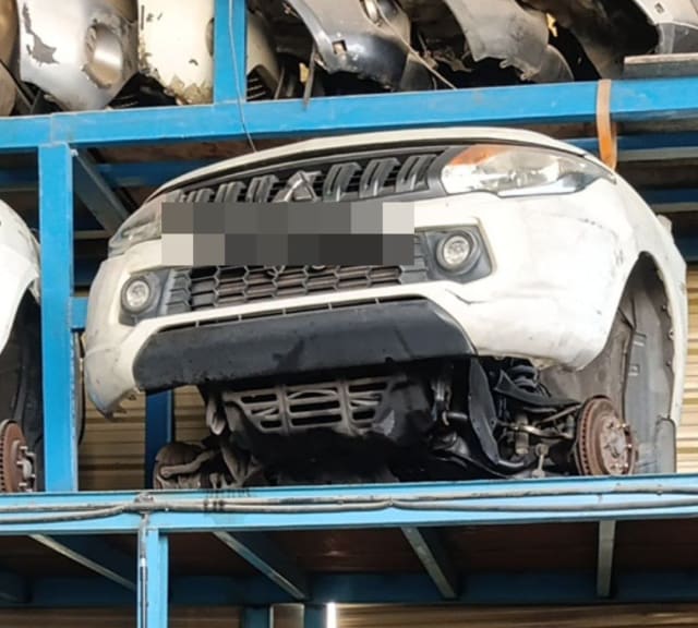 White Mitsubishi L200 front halfcut on rack — bumper, grille, headlight and suspension, Sharjah market
