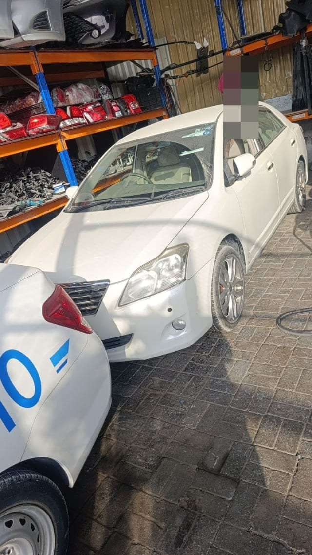 White Toyota Premio sedan for parts — front bumper, grille, headlights and alloy wheels, Sharjah market