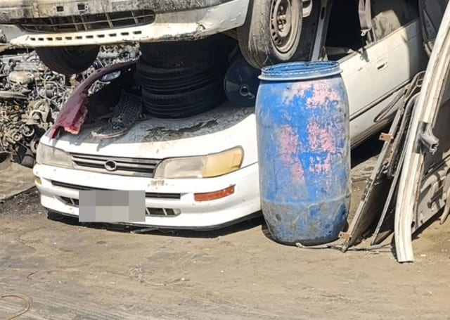 White Toyota Corolla sedan halfcut: front bumper, grille and headlights, tires stacked on hood, Sharjah market