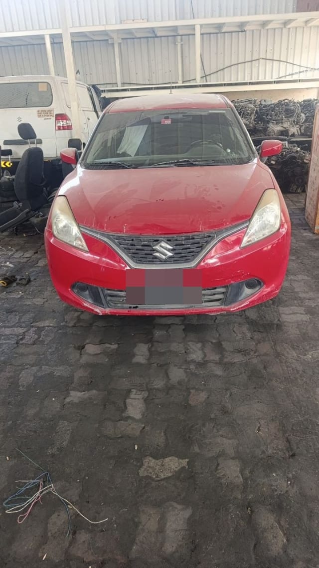 Red Suzuki Baleno hatchback for parts, front view with bumper, grille, hood and headlights, Sharjah market