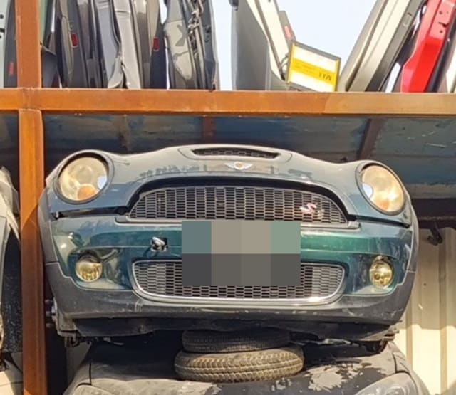 Dark green MINI Cooper S front halfcut with hood, headlights, grille and bumper on a rack, Sharjah market