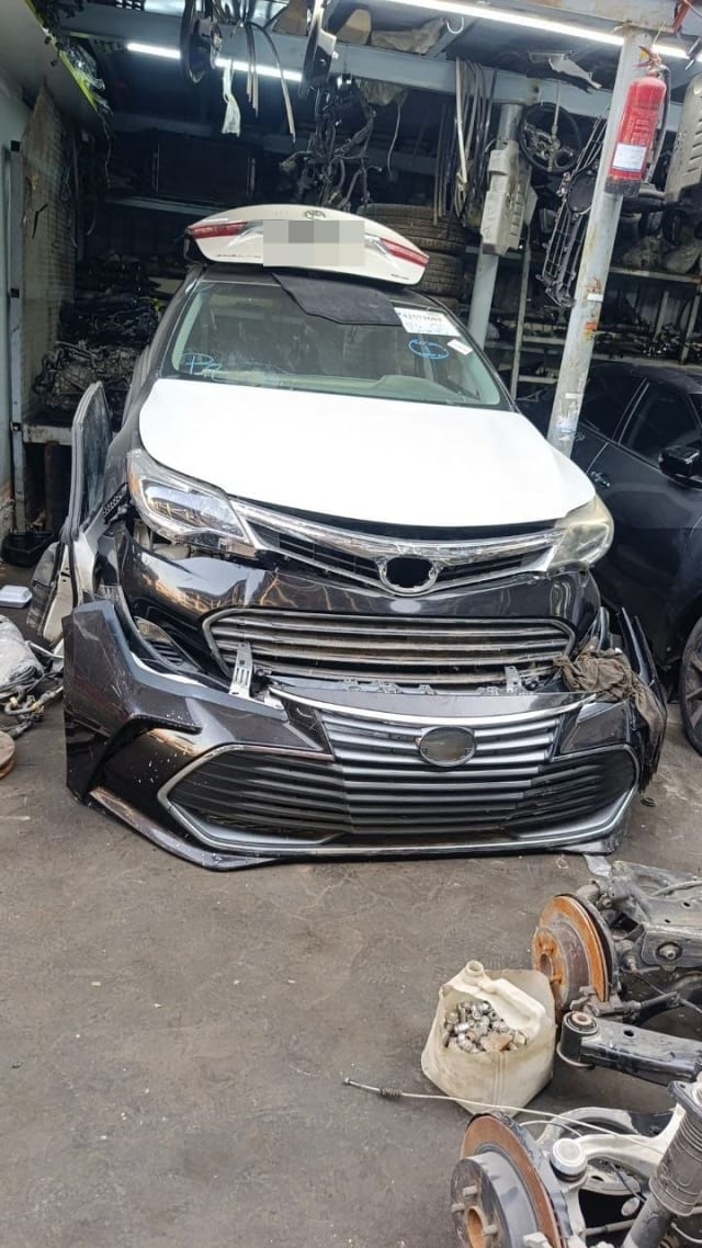 White Toyota Avalon sedan for parts — hood, headlights, detached front bumper and grille, Sharjah market