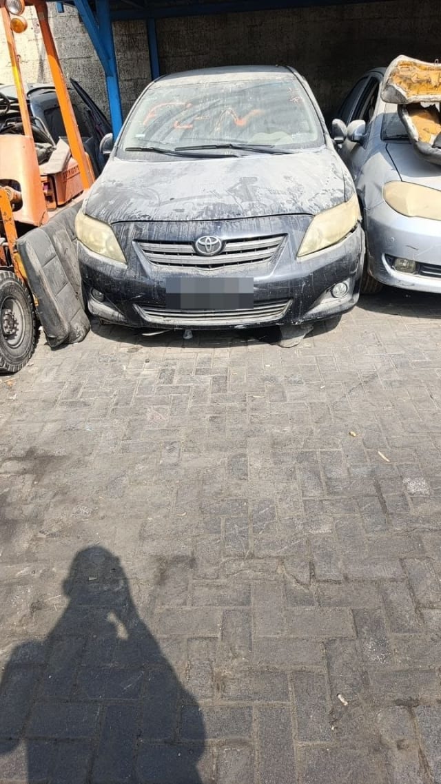 Dusty dark grey Toyota Corolla sedan for parts — front bumper, grille, headlights and hood, Sharjah market