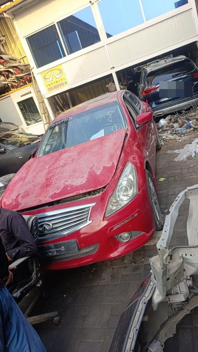 Red Infiniti G Sedan halfcut front view: bumper, chrome grille, headlights and faded hood, Sharjah market
