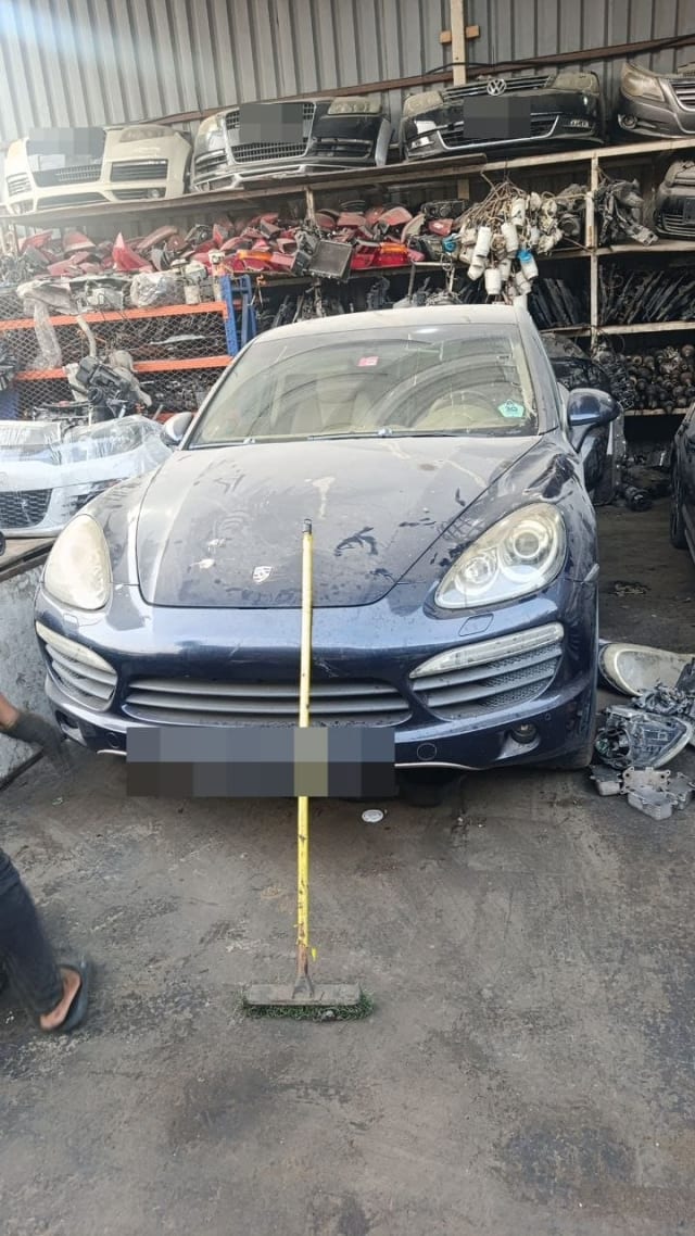 Dark blue Porsche Cayenne halfcut front end with hood, headlights and bumper in a Sharjah market parts shop