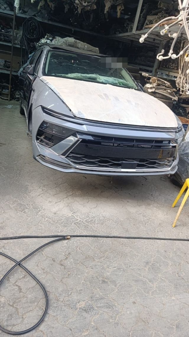 Light grey Hyundai car for parts, front view with bumper, grille, headlights and wrapped hood, Sharjah market