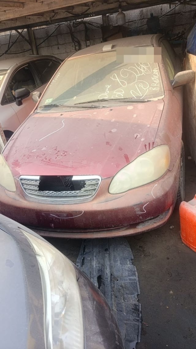 Dusty dark red Toyota Corolla sedan for parts, front view with hood, bumper, headlights and grille, Sharjah market