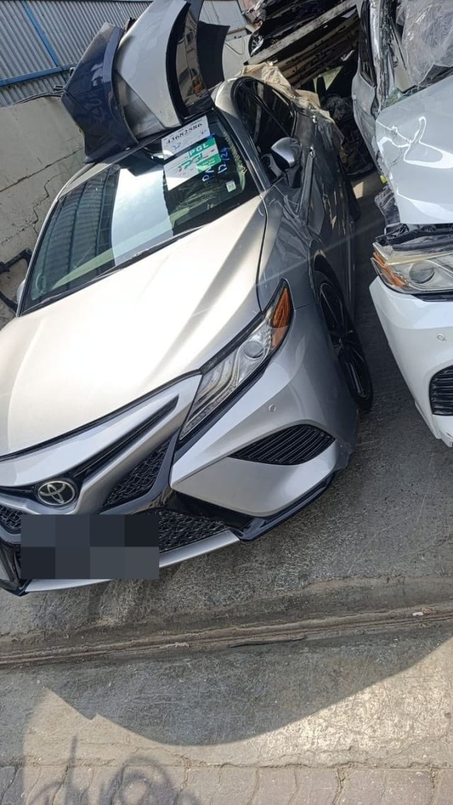 Silver Toyota Camry sedan front cut — bumper, black mesh grille and headlights, Sharjah market