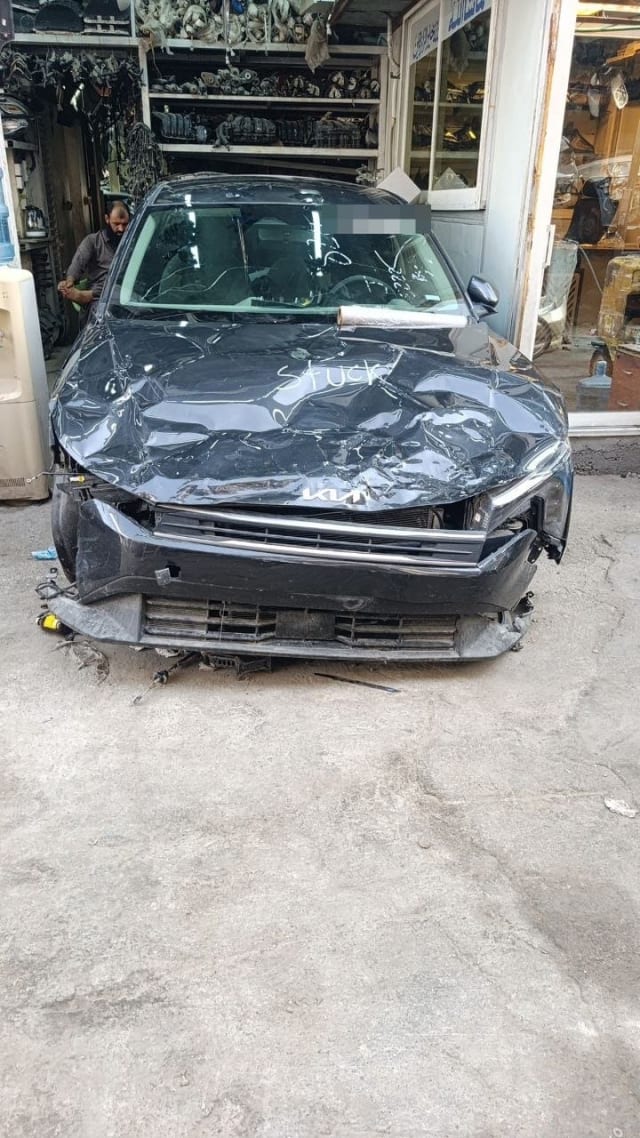 Dark grey Kia car for parts with crumpled hood, front bumper and grille, Sharjah market