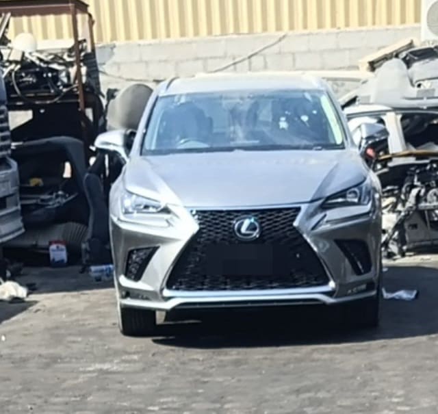 Silver Lexus NX SUV halfcut front view: spindle grille, headlights, bumper and hood, Sharjah market