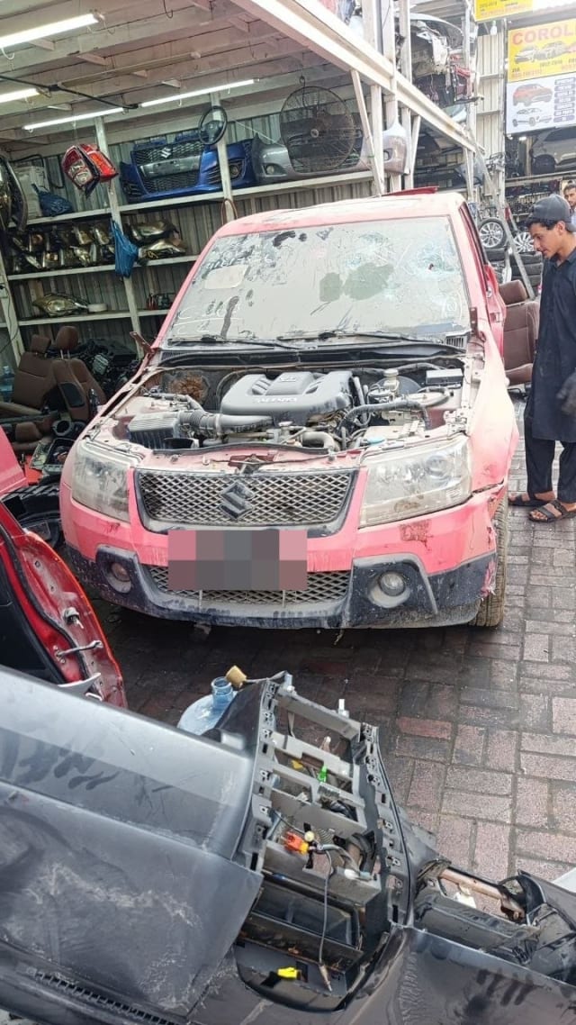 Red Suzuki Grand Vitara SUV for parts, hood off showing engine, grille and headlights, Sharjah market
