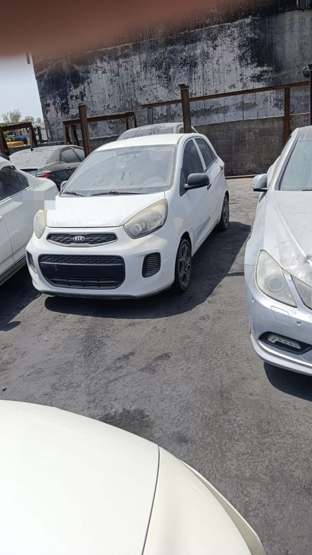 Dusty white Kia Picanto hatchback for parts — front bumper, grille, headlights and doors, Sharjah market