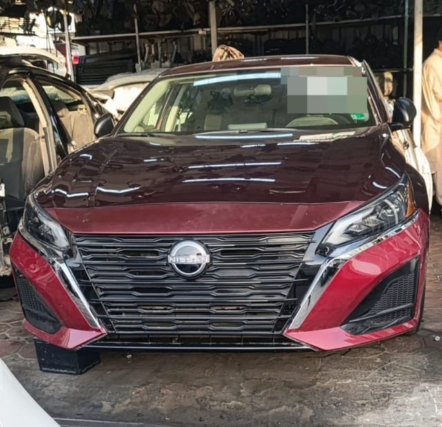 Dark red Nissan Altima sedan for parts, front view with hood, grille, bumper and headlights, Sharjah market