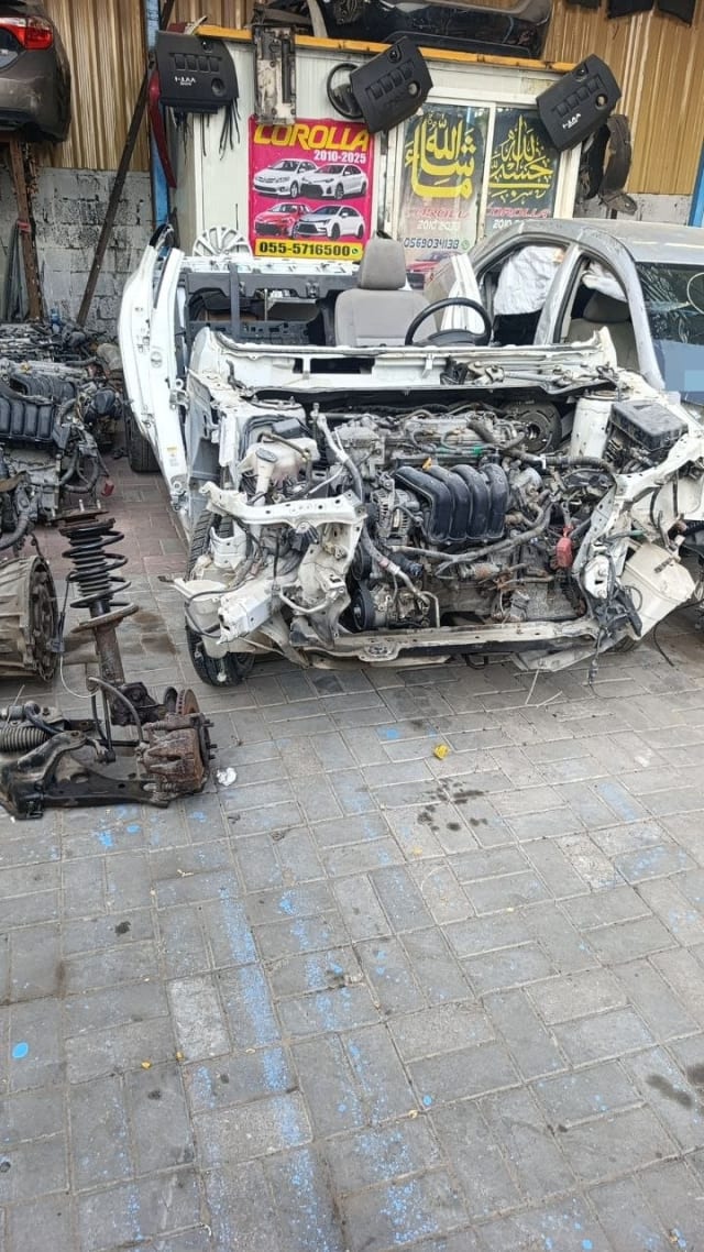 White Toyota Corolla halfcut with exposed engine and stripped front end, Sharjah parts market