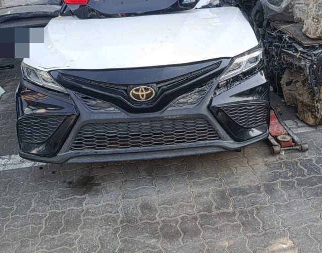 White Toyota Camry sedan front cut — black sport bumper, mesh grille and headlights, Sharjah market