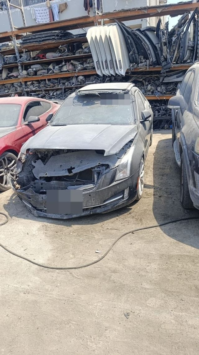 Dark grey Cadillac ATS sedan halfcut with crushed front bumper and damaged hood, Sharjah parts market