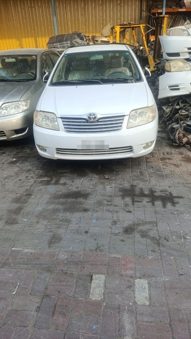 White Toyota Corolla sedan for parts, front view — bumper, grille, headlights and hood, Sharjah market