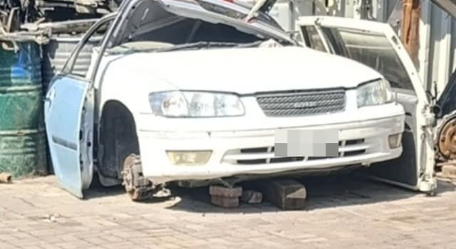 White Toyota Camry halfcut on blocks: front bumper, grille, headlights and hood at the Sharjah market
