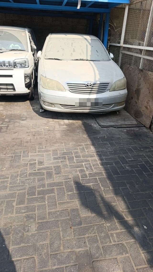Dusty silver Toyota Camry sedan for parts — front bumper, chrome grille and headlights, Sharjah market