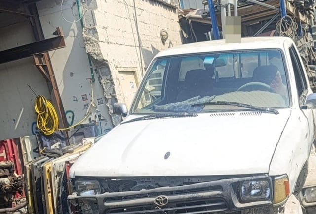 White Toyota Hilux pickup for parts — hood, grille, headlights and cab, bumper missing, Sharjah market