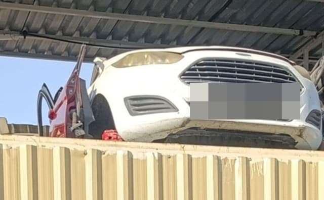 White Ford Fiesta halfcut front cut with bumper, grille and headlight on a rack, Sharjah market