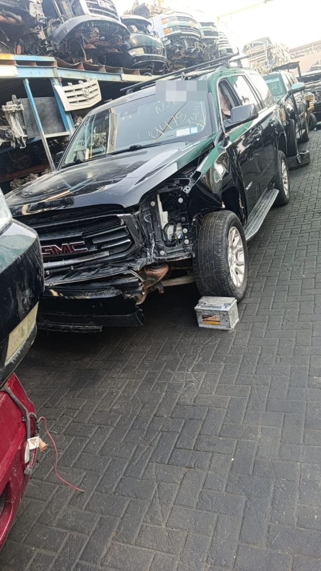 Black GMC Yukon SUV for parts with damaged front fender area, grille and hood visible, Sharjah market