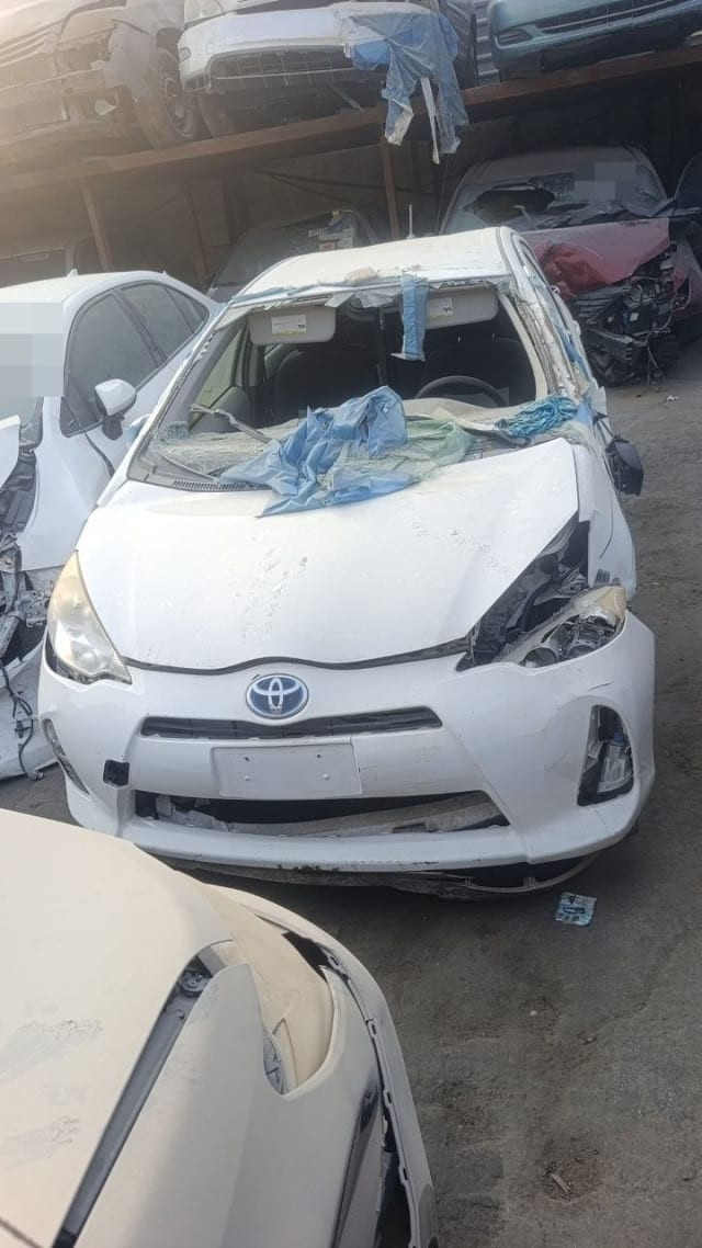 White Toyota Prius c / Aqua car for parts, front view with bumper, hood and headlights, Sharjah market